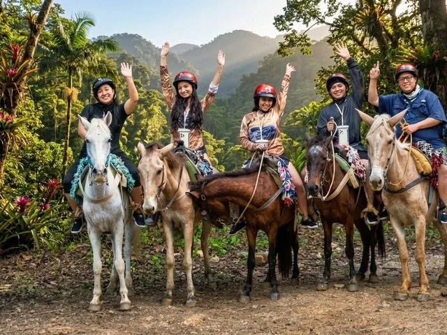 Gruppo di persone a cavallo in una foresta tropicale.